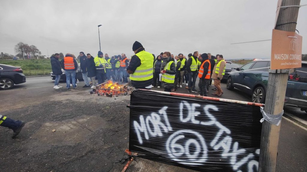 Photo of taxi drivers behind a “Death of taxis 60” sign at the arrival of the RN 31 in Beauvais.