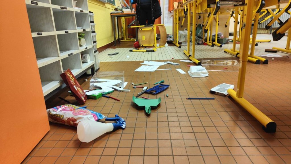 Photo of the floor littered with broken objects in a classroom.