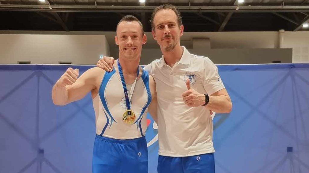 Erwan Le Rouzo, gold medal around his neck, poses with his coach Thomas.