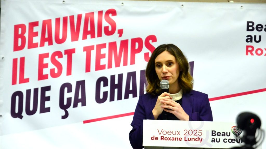 Photo of Roxane Lundy at the microphone in front of her slogan Beauvais, it's time for a change!