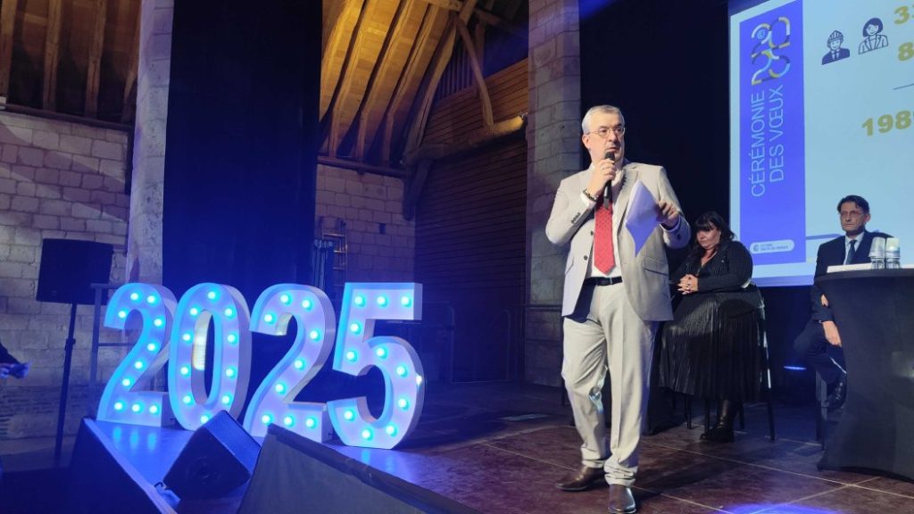 Photo by Philippe Bernard on stage with a light panel "2025" Next to him.